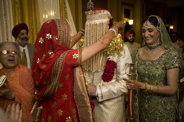 The bride and groom present each other with floral garlands at a wealthy Sikh wedding.