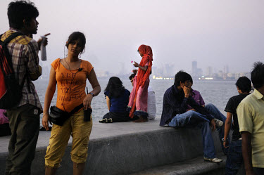 Young girl begging from middle class youths enjoying the dusk on Marine Drive.