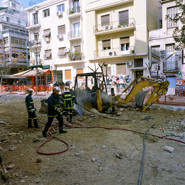 The fire brigade extinguish a burning Caterpillar digger set alight by a group of anarchists in protest against the construction of a parking lot in Trikoupi Street in the heart of the Exarchia neighb...