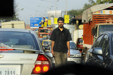 Pedestrian walking down the central divider of a highway blocked on both sides by traffic jams.