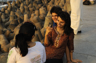 Middle class friends taking photos with a mobile telephone on Marine Drive waterfront at the weekend.