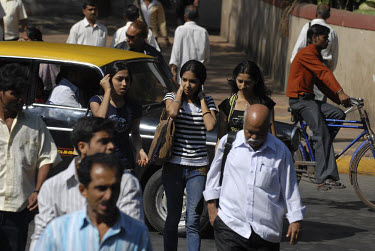 Young middle class girls walking along a crowded main street in central Mumbai.