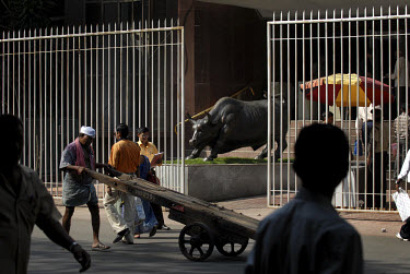 Investors and the public walking past bronze bull statue at the entrance to the Stock Exchange.