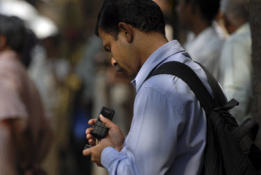 An investor checks one of his two mobile phones outside of the Stock Exchange.