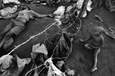 A child looks at dead bodies through a razor wire fence in the Kibeho camp. Over 4,000 Hutus were killed on 22/04/1995 during an operation by the Tutsi Rwandan army to clear the Kibeho refugee camp. T...