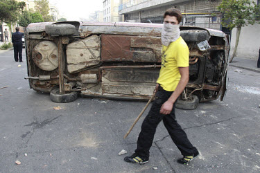 A demonstrator on Khosh Street beside an overturned car. Following a disputed election result, thousands of supporters of opposition candidate Mir-Hossein Mousavi took to the streets in protest.