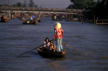 A Vietnamese woman ferries school children home across a branch of the Mekong River.