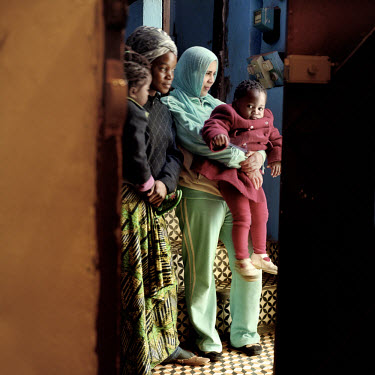 An 18 year old Congolese refugee mother of two stands with her children and one of the Moroccan women who took them into her home, in the G5 area of Rabat.