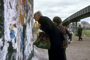 An elderly East German couple eat a banana, which were in short supply in East Germany, as they peer back towards the East from the West side of the Berlin Wall in the days after its fall.