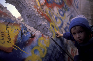 A child looks through a gap in the Berlin Wall in the days after its fall.