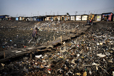 A man crosses a severely polluted river in the suburb of Agbogbloshie. When the rains come much of this waste will be washed to the sea. Agbogbloshie dump has become a dumping ground for computers and...
