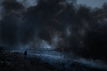 Smoke from burning e-waste drifts along the edge of Agbogbloshie dump, which has become a dumping ground for computers and electronic waste from all over the developed world. Hundreds of tons of e-was...