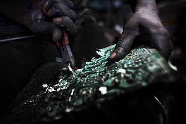 A man rips apart a circuit board to salvage components, at Agbogbloshie dump, which has become a dumping ground for computers and electronic waste from all over the developed world. Hundreds of tons o...