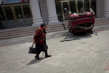 A Uighur woman passes a car overturned during riots. Ethnic violence between the Uighur and Han Chinese people had erupted in the city a few days earlier.