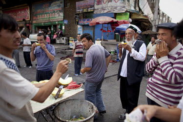 Uighur men eat melon in the Uighur district of Urumqi.