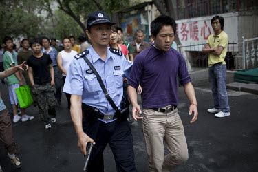 A policeman arrests a Han Chinese man who was part of a mob that chased down a Uighur in Urumqi. They caught up with the Uighur and beat him before the police intervened firing shots in the air and ar...