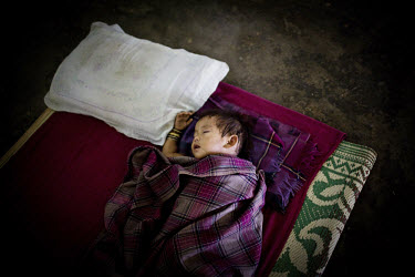 A young child from Mabauram village, whose house was torched by suspected Dimasa militants, sleeps in Zeme cultural hall in Lodi village in Upper Haflong. Recent ethnic clashes between the Dimasa and...