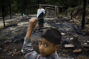 Ronsomo Langthasa stands on the spot where her house once stood, while her son Sanjit looks on. On the 8th of May 2009, suspected Zeme Naga militants burnt down 10 of the 13 houses in the Dimasa villa...