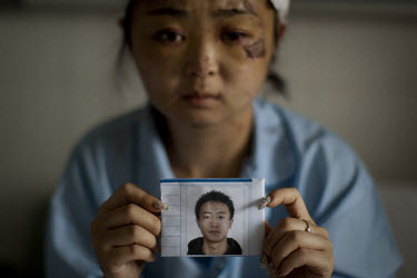 24 year old Dong Yuanyuan holds a photograph of her missing husband as she recovers in the Number 2 Hospital in Urumqi. She is an air stewardess teacher who was beaten up with her husband on a bus and...