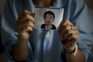 24 year old Dong Yuanyuan holds a photograph of her missing husband as she recovers in the Number 2 Hospital in Urumqi. She is an air stewardess teacher who was beaten up with her husband on a bus and...