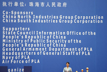 A ceremony hostess stands by a poster stating the name ofsponsors at the 2008 China International Aerospace and Aviation Exhibition in Zhuhai.