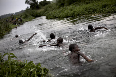 Children from a nearby IDP (Internally Displaced Persons) camp swim in a river running through the town of Kitchanga.