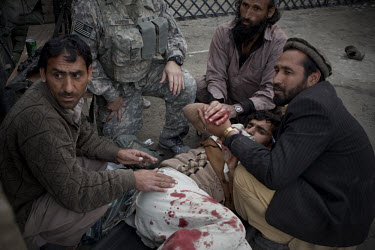 Khan Bacha, from Assadabad, an Afghan worker on the US Army Korengal Outpost is helped after being wounded by a mortar and grenade attack on the base in the restive Korengal Valley. Khan was treated f...