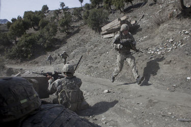US Army soldiers from Viper Company 126, 2nd Platoon, run for cover and return fire after being attacked on a foot patrol near Atabad in the restive Korengal Valley. The patrol was to meet with key tr...