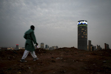 A member of a Zionist Christian church walks on a hilltop used as a place of worship near Yeoville in central Johannesburg. The Ponte Tower is in the background.