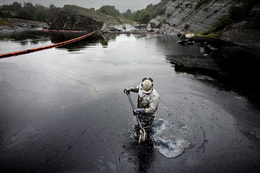 A man cleans some of the worst affected areas around Langesund following an oil spill. First the workers gather the oil, then a truck sucks it up. The 167 metre long cargo ship Full City ran aground a...