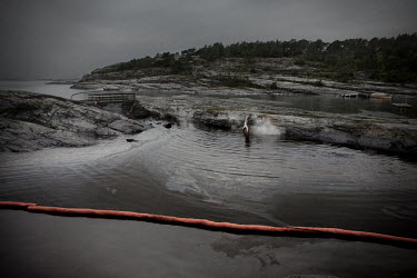 A man cleans some of the worst affected areas around Langesund following an oil spill. Warm water is used to wash the rocks. The 167 metre long cargo ship Full City ran aground at Saastein, just south...
