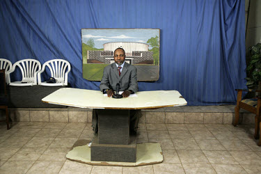 In the TV studio of Television Katanga (RTNC), the newsreader makes himself ready for the live broadcast. The station has only one studio, so the backdrop has to be hastily changed from the previous c...