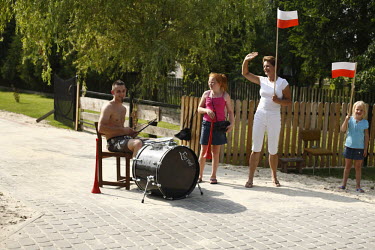 A man drums as people watch the Tour De Pologne bicycle race.