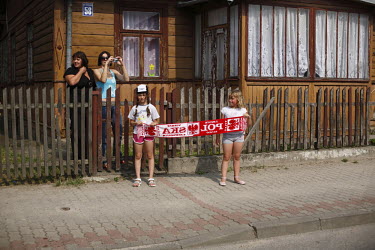 Children hold a Poland scarf outside their home as they watch the Tour De Pologne bicycle race.