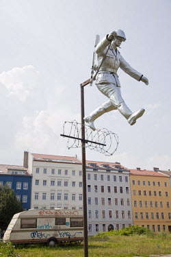 Sculpture recreating the famous photograph of an East German border guard jumping to freedom over the Berlin Wall in its early days of construction when it was little more than a barbed wire fence. Th...