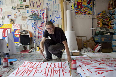 SP38, a French artist in his studio in East Berlin painting placards with the slogan ^Quality Street^. He posts the placards on the sides of buildings as an ironic comment on the gentrification of for...