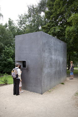 Berlin memorial to gay victims of the Nazis in the Tiergarten Park consists of a concrete block with a small window. Viewed through the window is a continually repeating video showing a gay couple kis...