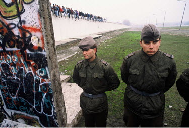 East German Border Guards look through a newly opened section of the Berlin Wall a few days after the opening of the Wall on November 9, 1989. In the background is the former ^death strip^, or no-man'...