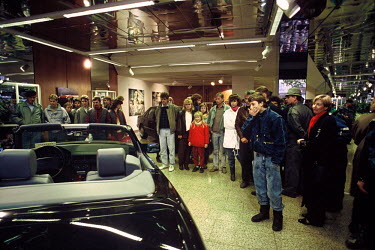 East Germans in a Mercedes showroom in West Berlin a few days after the opening of the Berlin Wall looking at high end sports cars the likes of which they had never seen before, except on television.