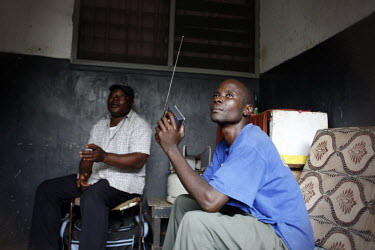 24 year old football fan Samuel Gizaza Sala, a refugee from Darfur in Sudan, listens to a live radio broadcast of the 2010 World Cup qualifying match between Ghana and Sudan. Next to him is 44 year ol...