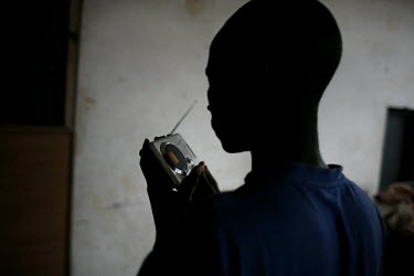 24 year old Sudanese refugee Samuel Gizaza Sala listens to the 2010 football World Cup qualifying game betwen Ghana and Sudan on the radio. Samuel and his family live out in the open under a tree in a...