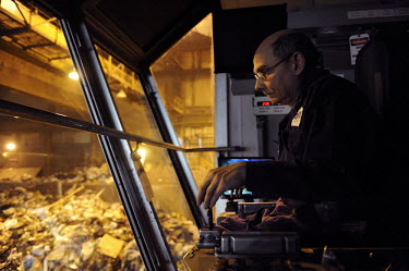 A crane operator at Covanta Waste-to-Energy plant, Westbury, New York. The plant feeds rubbish into giant furnaces that produce steam to turn a turbine and produce electricity.