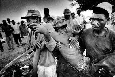 Haitian men carry 51 year old Marti Contrero away after he broke his legs whilst working with machinery on a sugar cane field in Barahona.