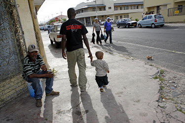 24 year old Richard Nifasha, a refugee from Burundi, walks home with his son through the neighbourhood of Kensington. He was a professional footballer and played for the Burundi national team before c...