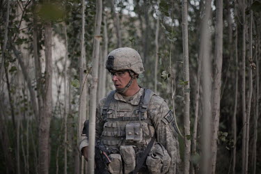A US Army soldier from 1st Platoon, Baker Company, 3rd Battalion, 509th Infantry Airborne walks through trees during an air assault operation to search for an IED (improvised explosive device) factory...