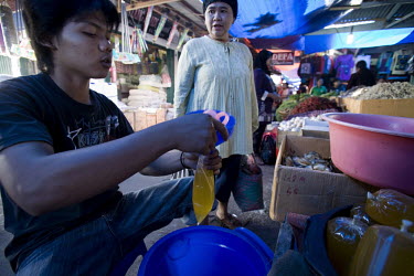 A vendor pours palm oil to be used for cooking into plastic bags, for sale in a market in Rengat.