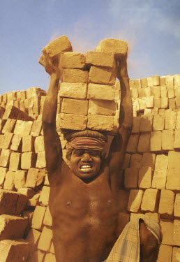 A young labourer carries bricks on his head at a brick factory outside Dhaka.