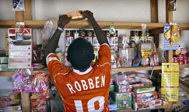 A boy wears an Arjen Robben Dutch football shirt and cleans shelves in a local shop in Gao. Many migrants travel to Europe with the dream to start a football career with a European club.