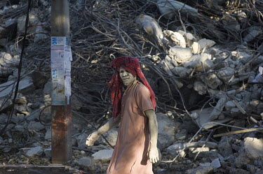 A voodoo believer walks past a pile of debris six days after an earthquake hit the city.A 7.0 magnitude earthquake struck Haiti on 12/01/2010. Early reports indicated that more than 100,000 may have b...