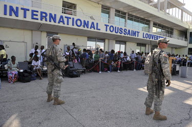 Haitians with American passports wait to get a flight to the United States while US Army soldiers guard the airport of Port-au-Prince five days after an earthquake hit the city.A 7.0 magnitude earthqu...